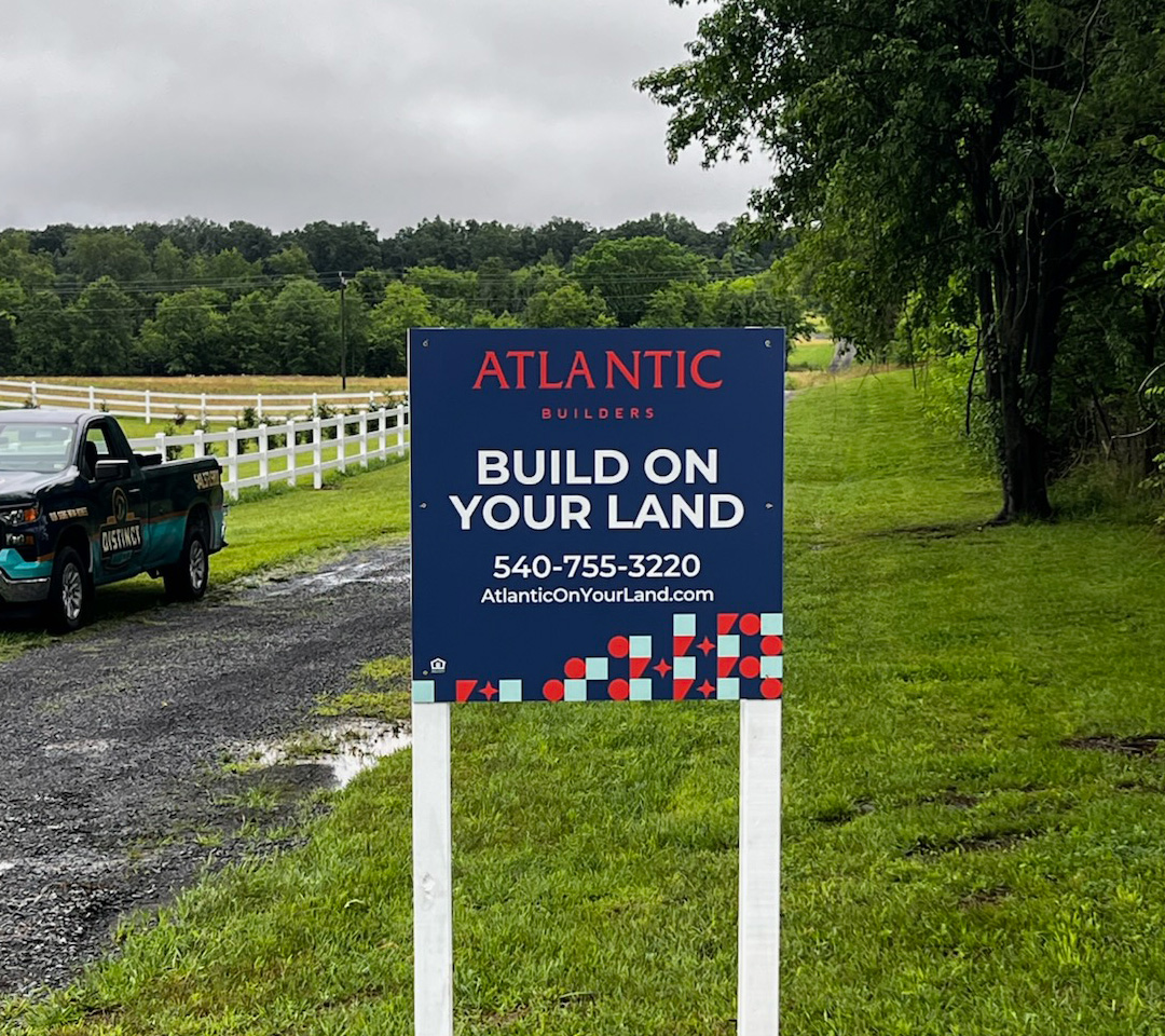 Atlantic Builders “Build On Your Land” custom home builder signs promoting local opportunities with contact information.
